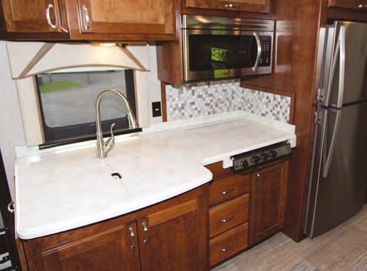 COACH FEATURE RENEGADE VALENCIA In the galley, a three-burner cooktop and a stainless-steel sink, both recessed, have solid-surface covers that match the rest of the countertop (above).