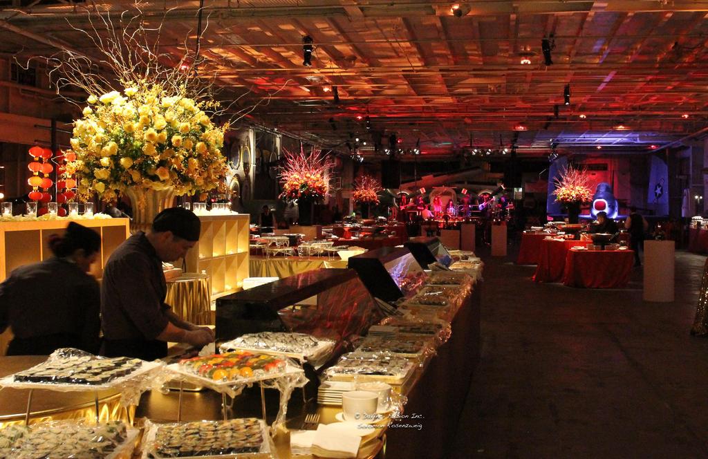 Buffet on the Hangar Deck with the stage in the background and atmospheric lighting.