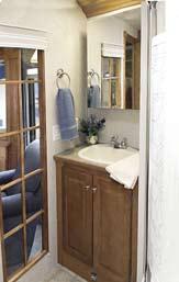 The bathroom features residential shower door and porcelain stool while the kitchen boasts abundant storage and workspace.
