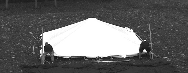 Step on the base plate to free both hands and lift one side of the tent frame.