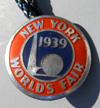 Lot # 240 - Silver Colored Adjustable ring with a disk on the front. "New York World's Fair 1939" around the edge and the center has the Trylon and Perisphere with the sunrise behind them.