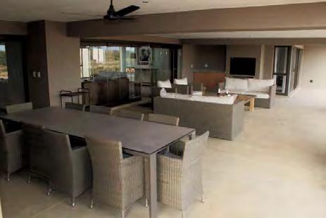 The lounge opens via frameless glass stackdoors onto an expansive undercover outdoor living area with built-in barbeque, comfortable