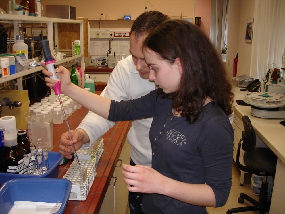 Fotografija 14: Delo v laboratoriju. Učenka raziskovalka Alisa s pipetorjem polni epruvete.
