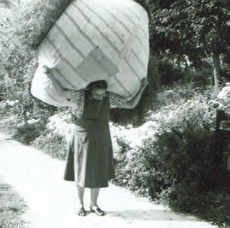 Žena iz Stare Fužine nese seno v rjuhi. 60. leta 20. stoletja. A women from Stara Fužina carrying hay in a sheet. 1960s. Svitek iz predpasnika. A head-cushion made from an apron.
