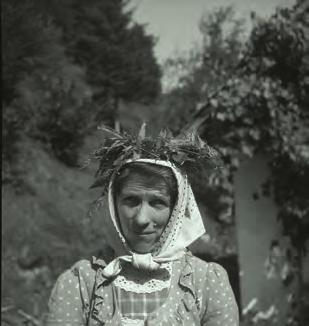 Raba za zaslužek Žena iz Troščin (vzhodno od Grosupljega) s hostnim svitkom (narejenim iz praproti) in z butaro drv na glavi leta 1949.