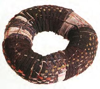 The second group consists of head-cushions in which the ring basis is divided by narrow coloured bands into quarters or thirds consisting of fabric strips of other colours.