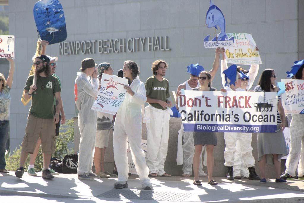 Protesters wave signs and shout chants against fracking Wednesday outside the