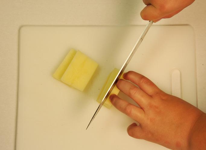 The sticks can then be cut into cubes. Cuts should be made by lifting the heel end of the knife off the cutting board, then slicing forward and down in a single smooth motion.