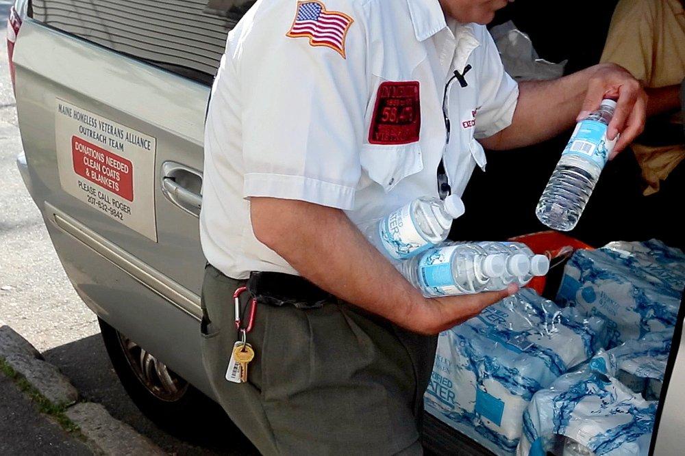 Goodoak fills his arms with bottles of water to hand out in