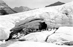 glacier ice and helped to start the current Repeat Photography Project. The 1932 photograph shows a guide, wearing chaps, and three clients next to the ice cave.