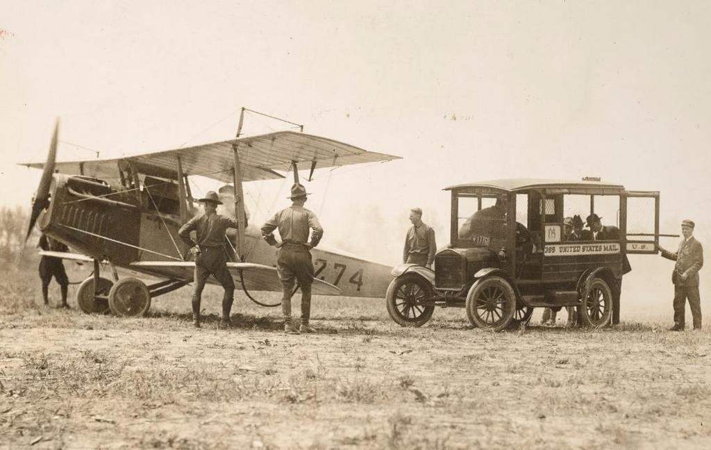 Airmail History in Pictures, 1918 1928 Mail is loaded onto a Curtiss JN-4H Jenny biplane on May 15, 1918, at Bustleton Field near Philadelphia, while U.S. Army personnel look on.