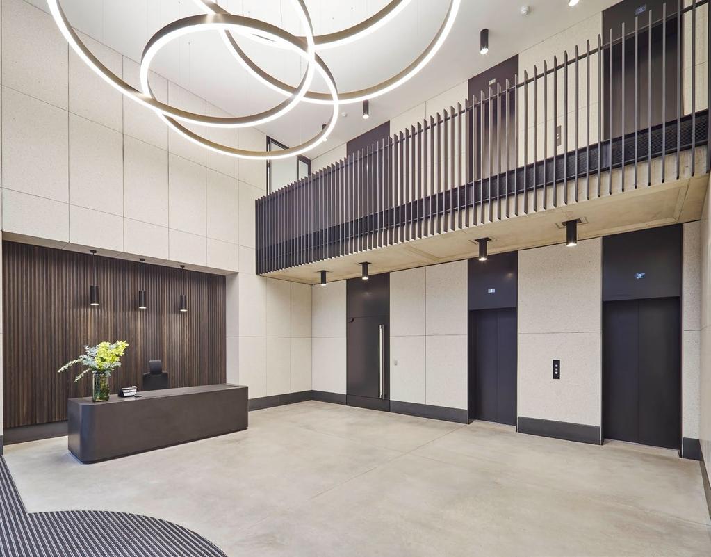 ABOVE A double height lobby with a polished concrete floor and reception desk creates space for a suspended, annular chandelier and a galleried walkway.