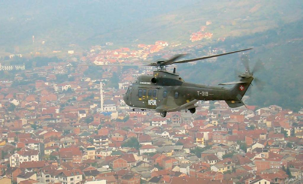 > Një helikopter zviceran I KFOR-it fluturon mbi Prishtinë, Kosovë: Nxitja e bashkëpunimit në operacionet paqeruajtëse drejtuar nga NATO është një fokus kyç i Partneritetit.
