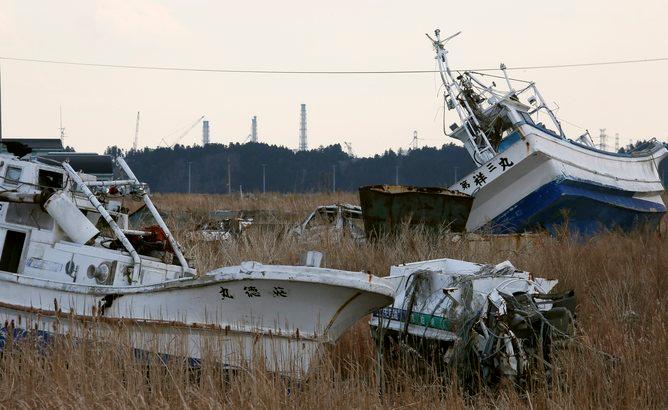 Fishing boats stranded by the 2011 tsunami, with the crippled Fukushima Daiichi nuclear power plant in the background.