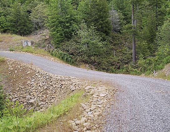Figure 4. This road has been surfaced with gravel to permit all-season use. Note armoring on stream crossing and dip in the road to prevent diversion of stream flow down the road if the culvert plugs.