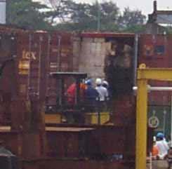 A container with fireworks from the M/V HANJIN PENNSYLVANIA is surveyed in Singapore. Note the cartons to the right and nearest to the door have heavy fire damage but the cartons to the left do not.