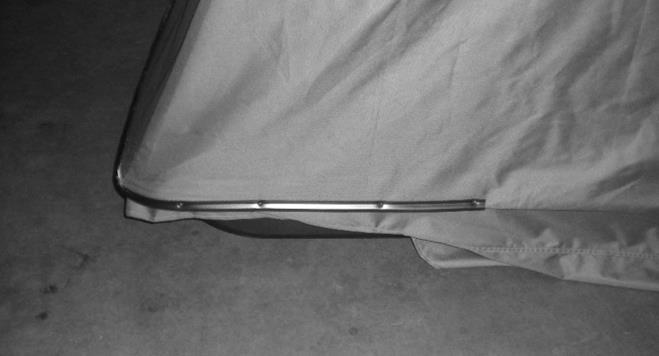 From behind the unit, pull the midpoint of the tent downward until the bottom hoop pole just starts to come off the ground. Secure the tent in this position with the U -channel molding.