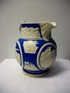 Lot # 10 - Cream and blue ceramic water pitcher. Along the top is a raised image of buildings, possibly burning to represent the great Chicago fire?