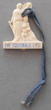 Estimate: $ 20-0 0 Lot # 181 - Plastic charm for "The Equitable Life" company. This figural charm was given out at the fair. Size: 7/8" wide by 1" high. Condition: Excellent.