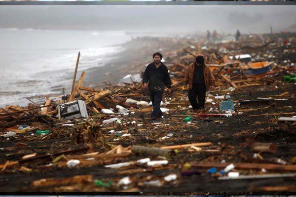 People walking along beach strewn with tsunami