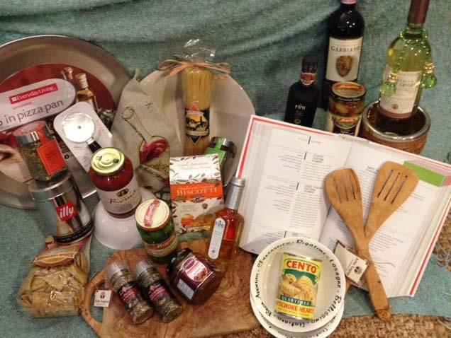 Auction Item #S32 La Dolce Vita Basket Basket of Italian foods and kitchen items including: pizza pan, pizza cutter, artichoke hearts, olive oil, balsamic vinegar, pesto, crostini, olives, pasta,