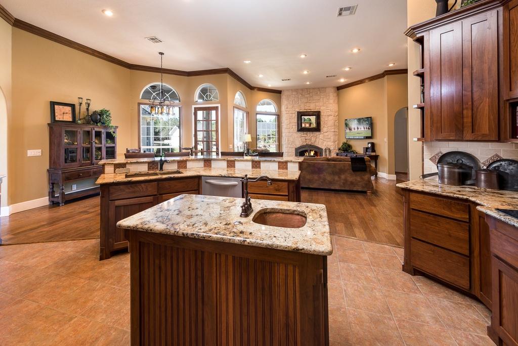 A chef s kitchen with center island and pantry leads to a large open area living room featuring a fireplace as