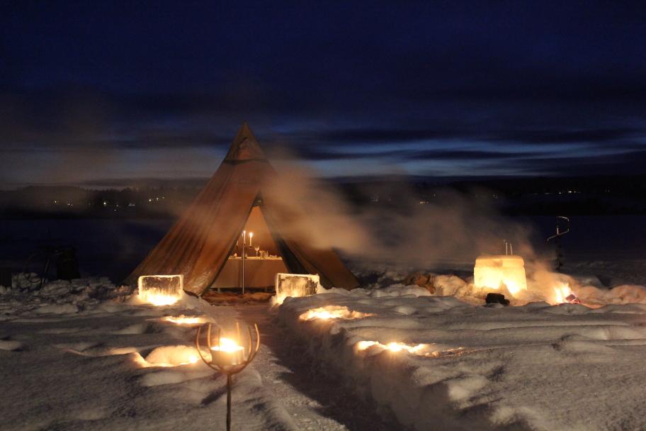 The evening is lit by torches and candles while a 3 course dinner is served in a heated tepee on an ice covered lake.