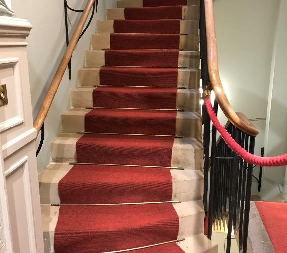 There is a rope handrail on both sides. The stairs surfaces are red carpet.