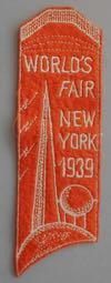Lot # 182 - Cloth Bookmark with embroidered Trylon and Perisphere with "World's Fair New York 1939" written down the right side. Size: 1 15/16" wide by 6 1/4" tall.
