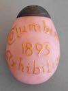 Lot # 19 - Pink Satin Glass Egg shaped Salt Shaker with raised letters "Columbian 1893 Exhibition" painted in gold. The bottom is stamped with a circle "Libbey Cut Glass Toledo O.