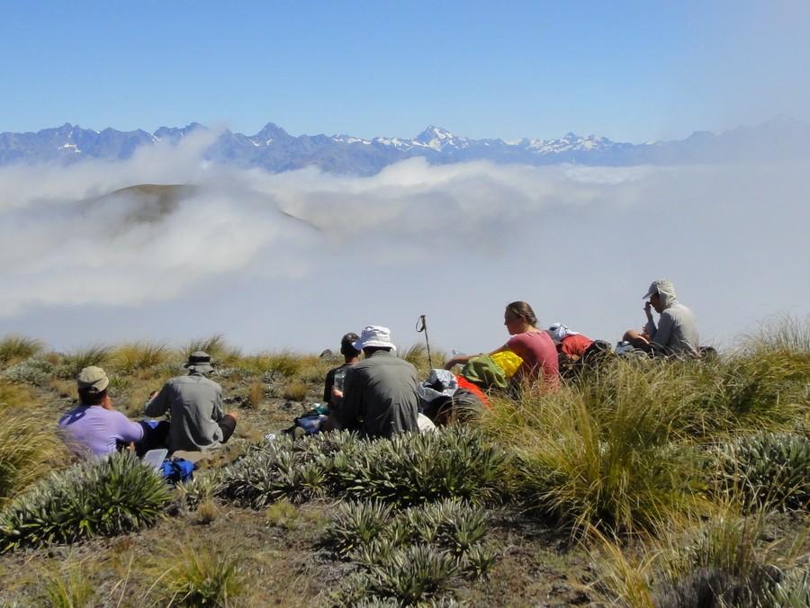 Lunch on Mt Harper With almost no wind, warm sun, and great view of island peaks above the cloud all around us, it was hard to get the party moving again, but eventually we were all heading along the