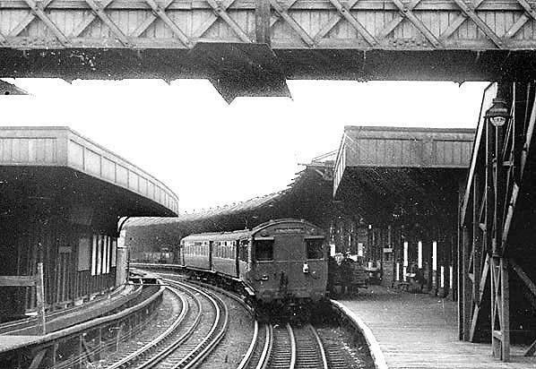 Looking east at East Ham (Left) with a six-car train of mixed Q Stock arriving. The unelectrified track at far left was used by the erstwhile Kentish Town East Ham steam service via the T&H.