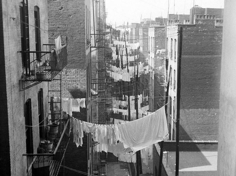 A view down an alley, as rows and rows of laundry hang from tenements ca.