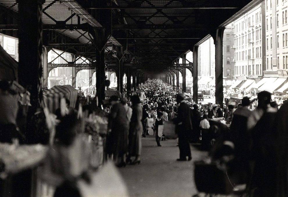 A crowded street market under New York City Rail Road tracks,