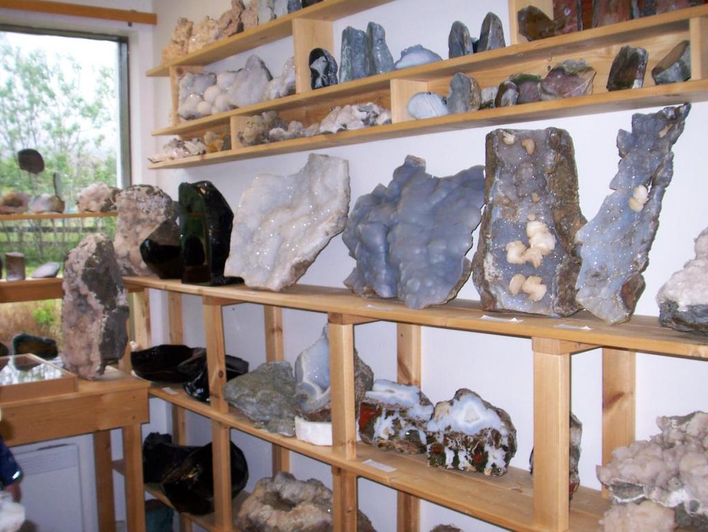 Kivimuuseumi riiul, kus tagapool paistavad süsimusta obsidiaani ja säravvalge kvartsi ülisuured eksemplarid.