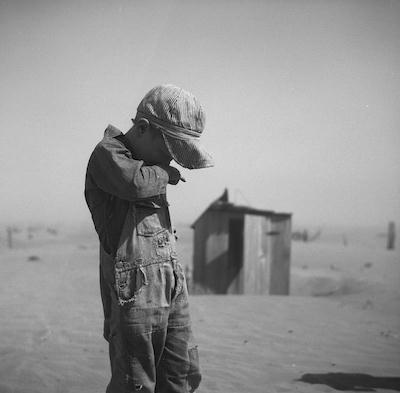A young boy covers his mouth during a dust storm on farm.