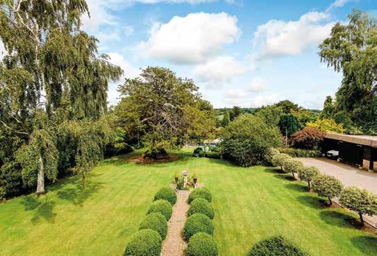 Well maintained lawns with shrub and flower borders slope gently away from the house to a majestic ancient yew tree and a raised circular paved barbecue area.