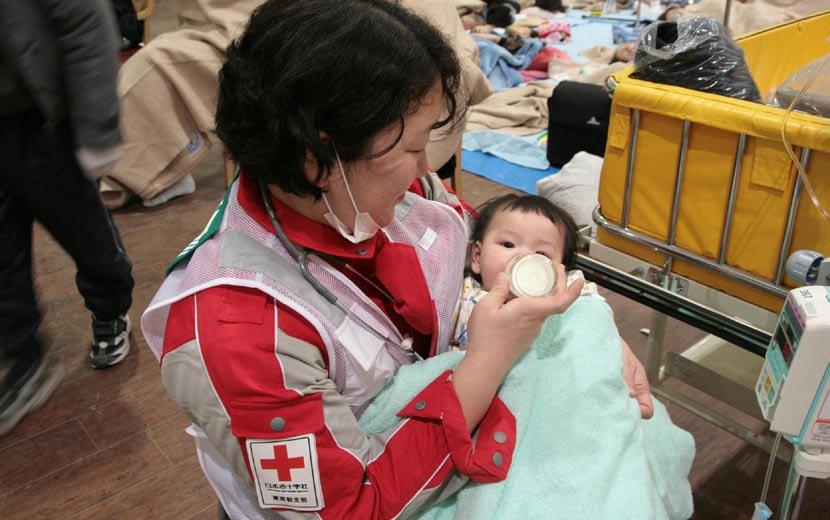 COVER STORY A member of the Japanese Red Cross feeds a baby at the Ishinomaki Red Cross Hospital in Miyagi Prefecture, March 12.
