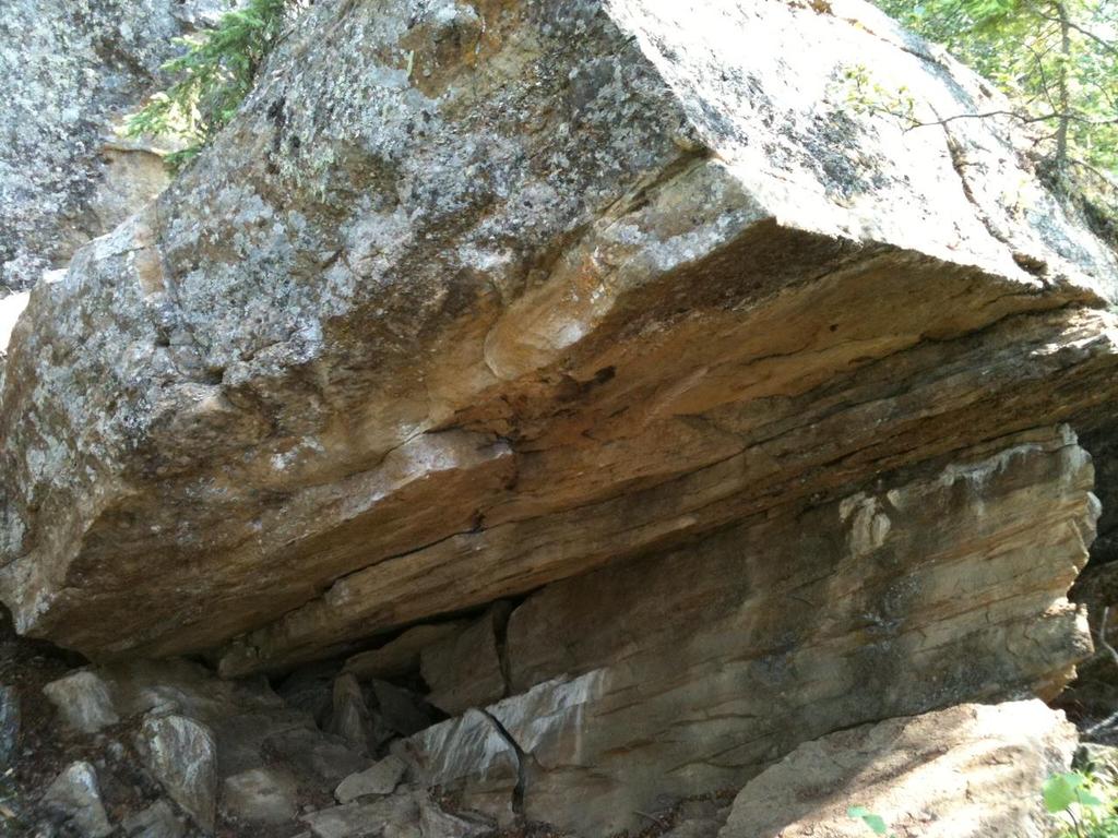 Following the main trail a short distance past the big overhanging cave, down the hill, and approximately 20m away from the cliff face, the distinctive overhanging boulder of Carlee s Cave can be