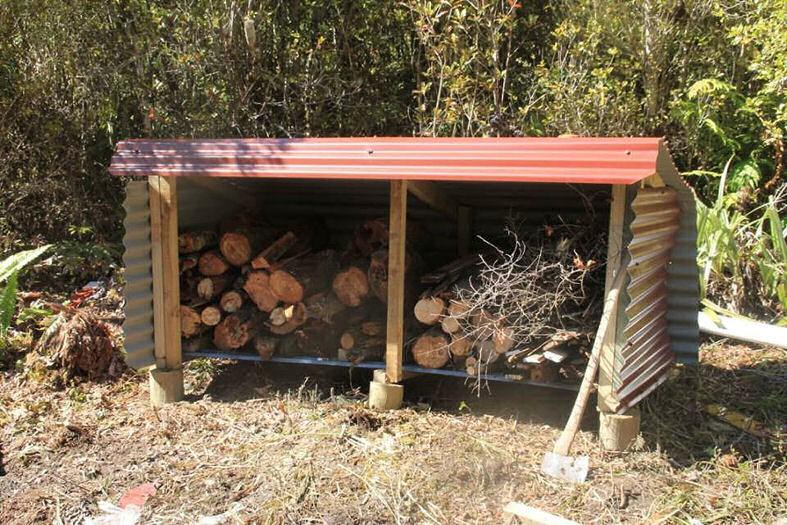 We then built a wood shed with timber off cuts and tin not used on the hut and tied it down with 4 strands of 12 gauge wire Wood shed full of wood and detail of tie down With the materials and