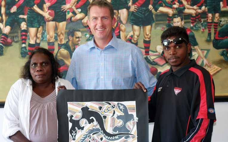Reconciliation Australia board member Djapirri Mununggirrity and son Dion present artwork to Essendon Football Club CEO & Managing Director, Ian Robson.
