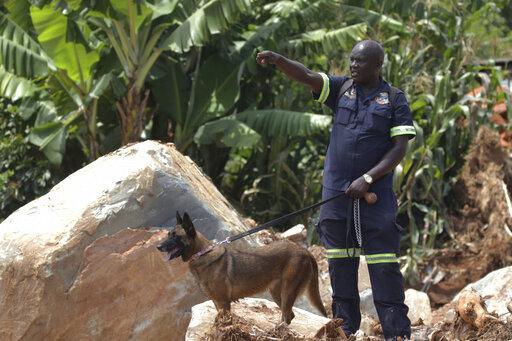 Photo/Tsvangirayi A South African Policeman guides his sniffer dog as they search through mud and rubble for bodies of those killed during Cyclone Idai near Chimanimani, Zimbabwe, Thursday, March 28,