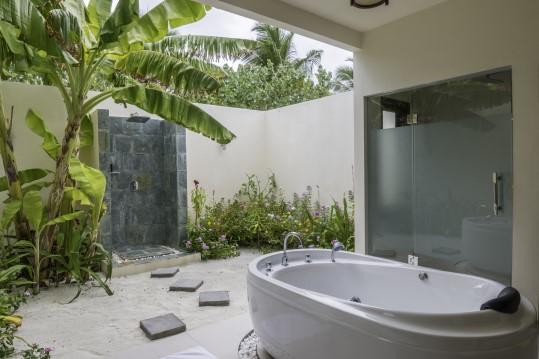 The semi-open air bathroom offers shower, a freestanding bath tube, twin vanities and an outdoor rainfall shower.