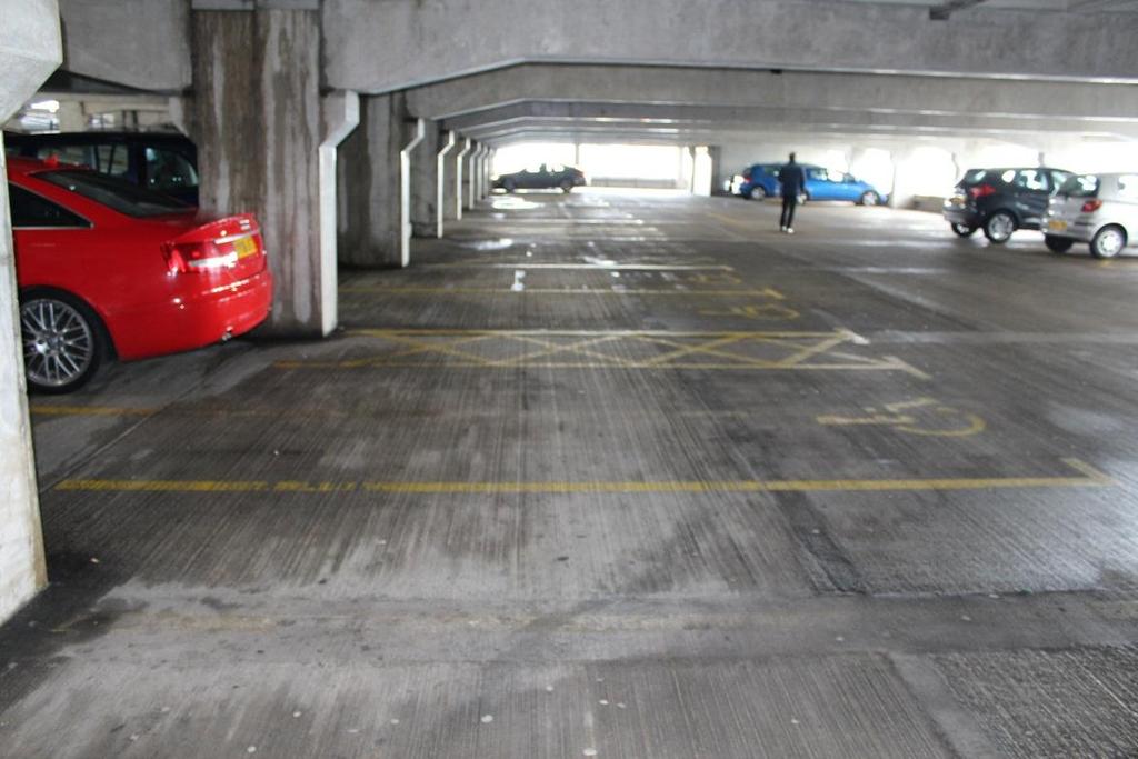 Ocean Terminal multi-storey parking. The surface of the multi storey car park is concrete. The car park is well lit.