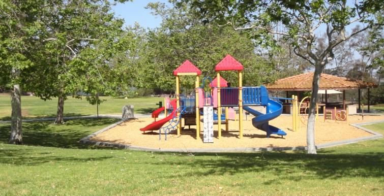 features two playgrounds and shaded benches under a gazebo.