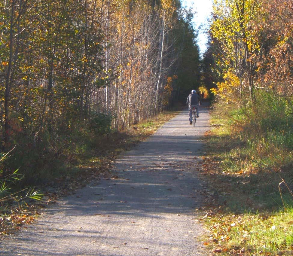 The trail passes through a forested area and begins to curve slightly, passing through the grounds of the Huronia Regional Centre (HRC).