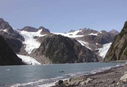 The photograph taken in 1909 (left) shows Holgate Glacier, a tidewater glacier at the head of the fjord with Little Holgate Glacier, one of its former tributaries, located to its left.