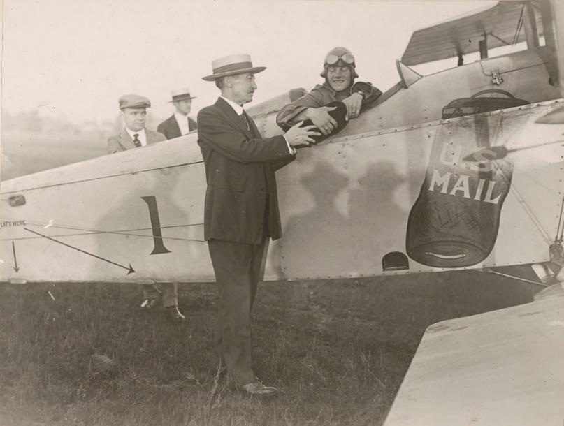 New York Postmaster Thomas Patten hands a mailbag to pilot Max Miller before Miller s pathfinding flight to Chicago on September 5, 1918.