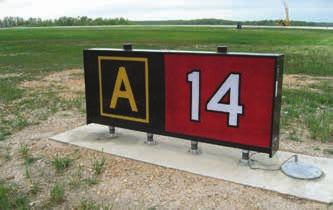 The sign has white characters outlined in black on a red background. It is always collocated with the surface painted holding position markings and is located where taxiways intersect runways.