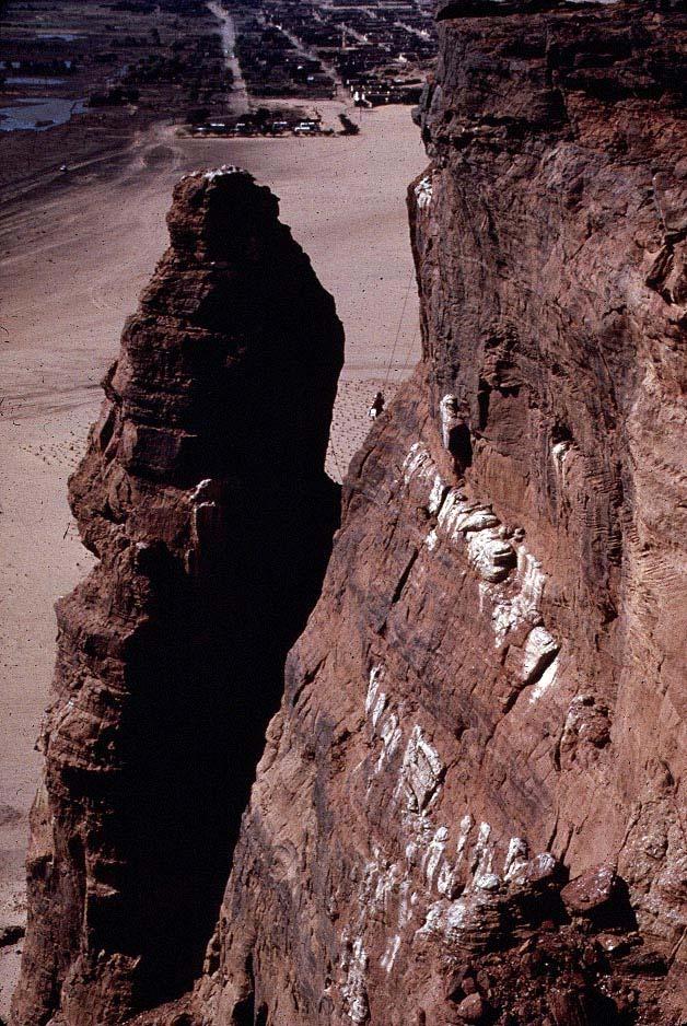 The pinnacle peak, when observed from the top of Jebel Barkal, is 11 m distant from - and 5 m below - the cliff edge across a deep gorge. Under normal conditions the peak is inaccessible.